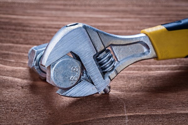 Adjustable spanner stainless bolt and screw nut on brown wooden board construction concept