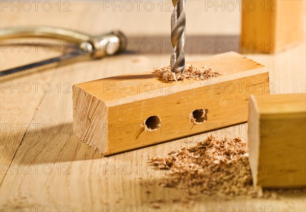 Drilling a hole in a wooden board on a table