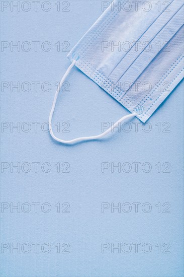 Disposable face mask on blue background with copy area vertical version