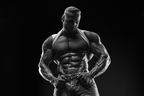 Silhouette of a strong bodybuilder. Confident young fitness athlete with a powerful body and perfect abs. Black and white photography. Dramatic light. Mixed media