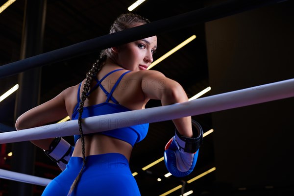 Powerful charged girl stands in the corner of the ring and is ready to explode in the next round. The concept of wrestling and boxing. Mixed media