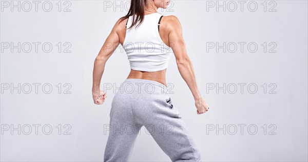 No name portrait. Young white fitness woman wearing sportswear standing over white wall background. Fitness concept. Mixed media