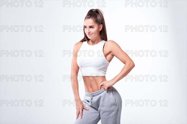 Young white fitness woman wearing sportswear standing over white wall background. Fitness concept. Mixed media