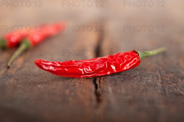 Dry red chili peppers over old wood table