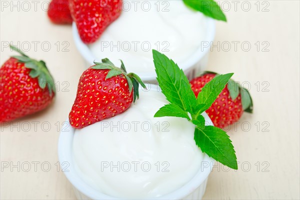 Organic Greek yogurt and strawberry over white rustic wood table