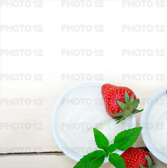 Organic Greek yogurt and strawberry over white rustic wood table