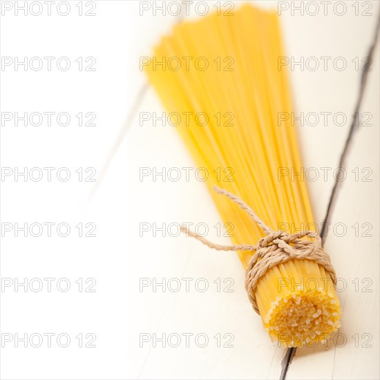 Italian pasta spaghetti tied with a rope on a rustic table