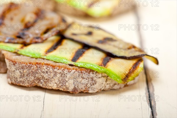 Grilled vegetables on rustic bread over wood table