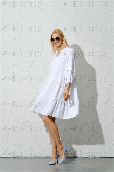 Cute woman in white cotton sundress and high heel shoes posing