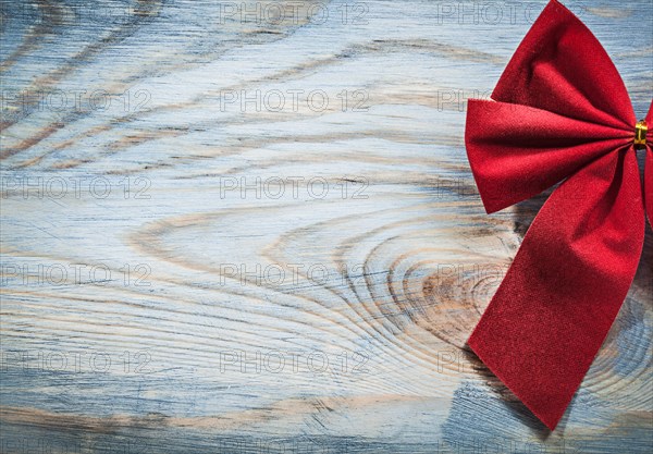 Red Christmas bow on wooden board copyspace holidays concept