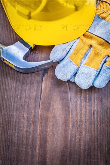 Construction concept claw hammer glove helmet on vintage wooden board with copyspace