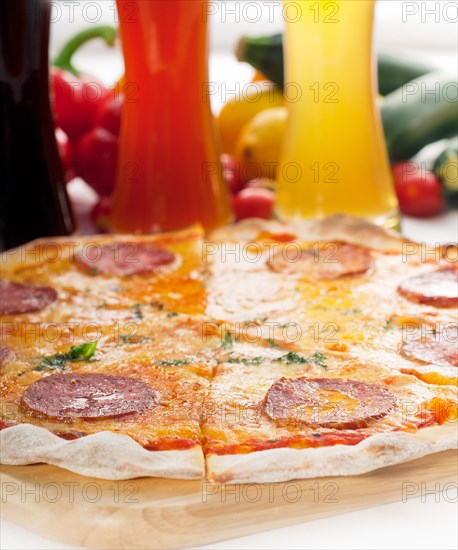 Italian original thin crust pepperoni pizza with selection of beers and vegetables on background