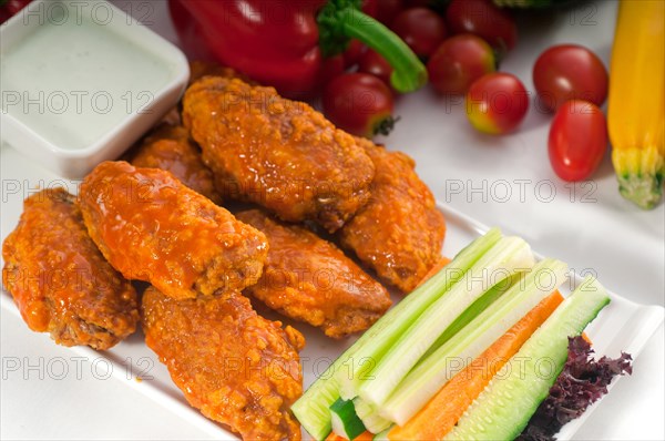 Classic buffalo chicken wings served with fresh pinzimonio and vegetables on background