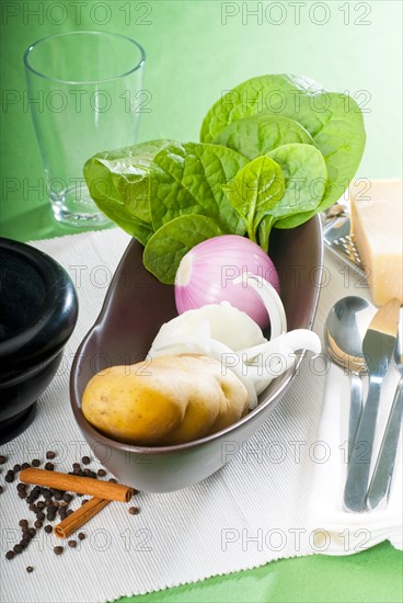 Bowl of fresh vegetable with spice and mortar beside