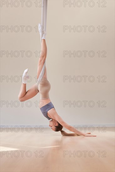 Image of a beautiful woman posing in a bright studio near the hammocks. The concept of airstretching. Fitness and sports