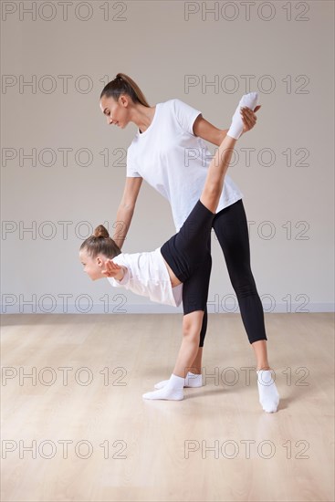 Beautiful woman teacher and a little girl perform dance movements in a bright studio. The concept of education