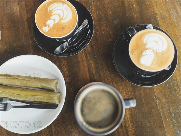 Two lattes with art and a black coffee served with Suman or budbud