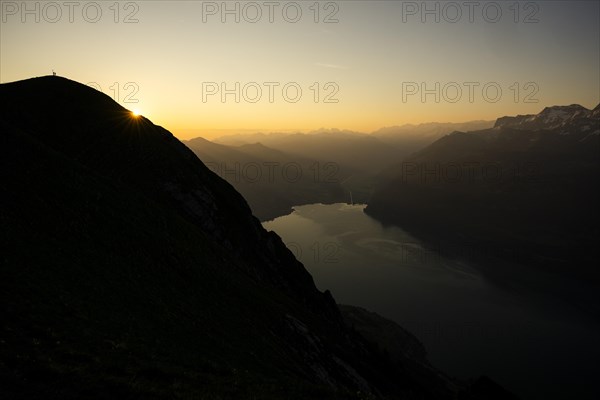 Mountain ridge with mountaineers and Swiss mountains and Lake Thun in the background at sunrise