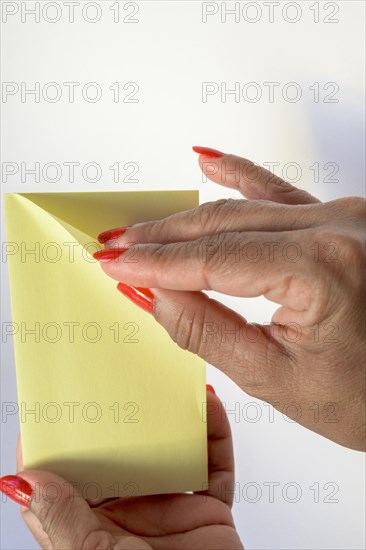 Woman's hand with painted nails holding blank letter paper on pure white background