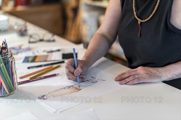 High angle of a fashion designer drawing a fashion sketch with colorful pencils