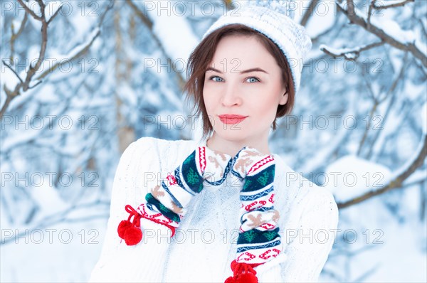 Portrait of a beautiful woman against the background of a winter forest in New Year's mittens. Concept of Christmas