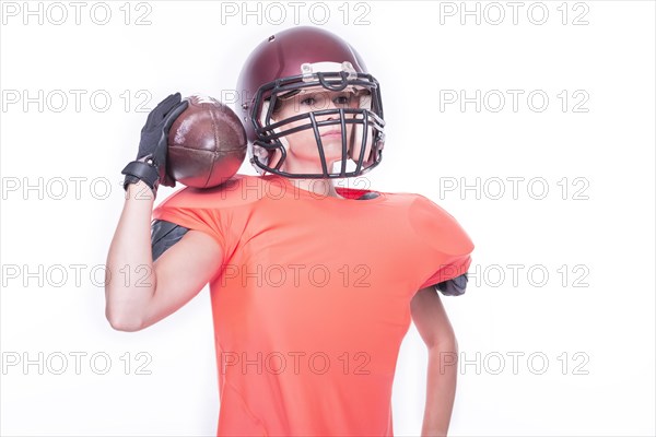 Woman in the uniform of an American football team player posing with a ball on a white background. Sports concept.