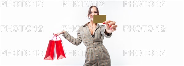 Charming brunette posing in the studio with red packages and a bank card. Gift concept. Shopping before the holidays. White background.