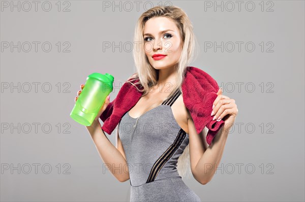 Charming model posing in the studio with a shaker in her hands and a towel around her neck.