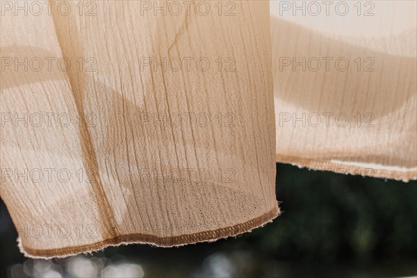 Sheer beige curtains fluttering with a soft and airy texture illuminated by sunlight