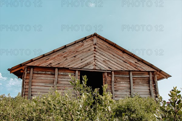 Wooden hut with a peaked roof against a blue sky. Kampot
