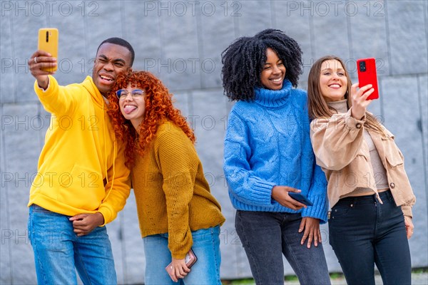 Multi-ethnic young people taking selfies standing in an urban space