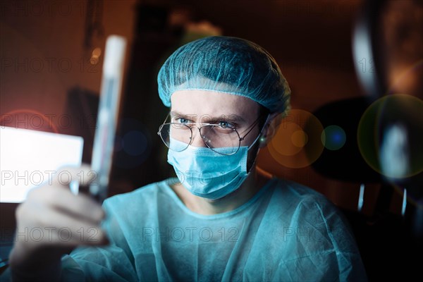 Scientist doctor in a dark laboratory with a test tube of a medicinal product