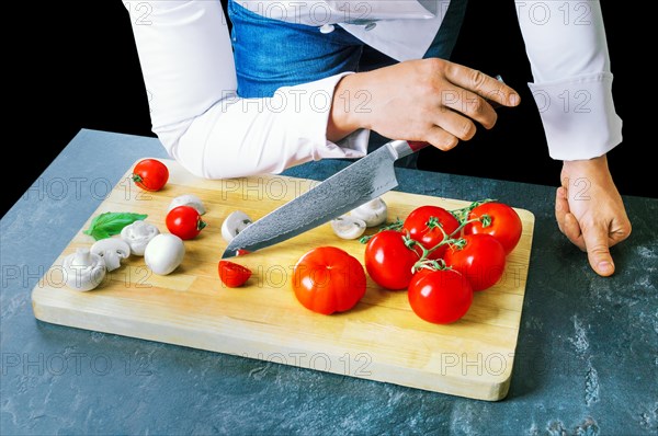 Professional chef cuts vegetables with a sharp knife from Damascus steel.