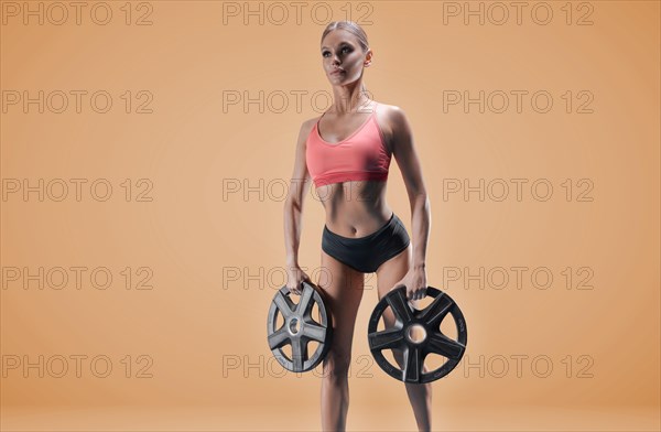 Delightful athlete posing in the studio with weights in her hands. The concept of sports