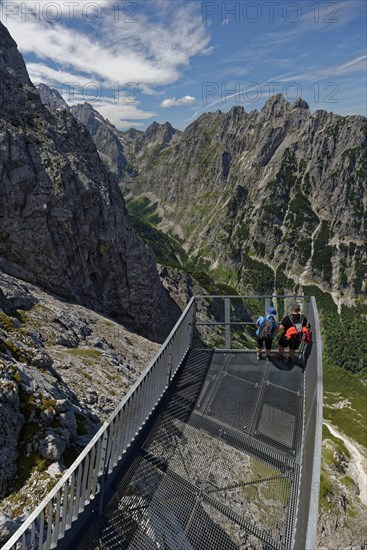 Hikers enjoy the view from a platform in a mountain range