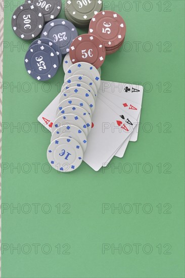 Poker chips neatly arranged with playing cards featuring aces on a green felt surface
