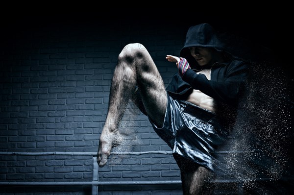 Thai boxer in the ring hits with a knee. The concept of sports