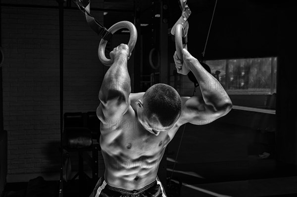 Athlete does warm-up on gymnastic rings. The concept of sport and healthy lifestyle.