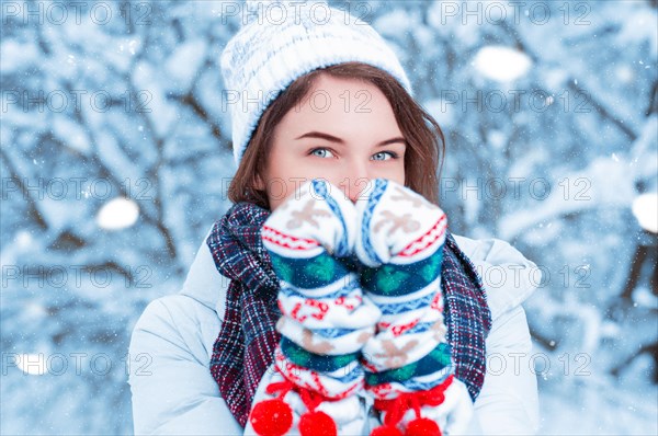 Portrait of a beautiful woman against the background of a winter forest in New Year's mittens. Concept of Christmas