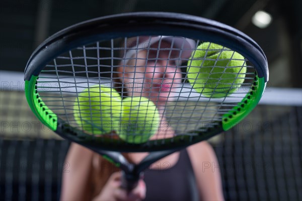 Image of a set of tennis balls lying on the strings of a racket. Sports concept.