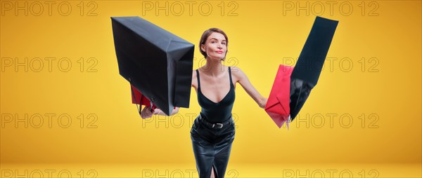 Cheerful positive girl jumps up with happiness and waving shopping bags. The concept of holiday gifts