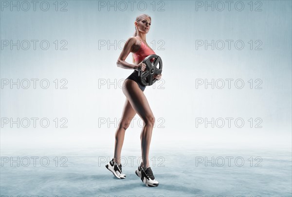 Delightful athlete posing in the studio with weights in her hands. The concept of sports