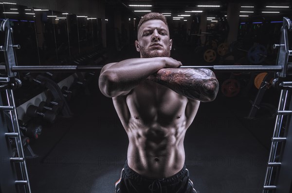 Portrait of an athlete performing front squat with a barbell in the gym. Bodybuilding and fitness concept.