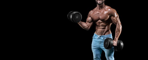 No name sexy muscular man in jeans posing on against a black background with a dumbbell. Bodybuilding and fitness concept.