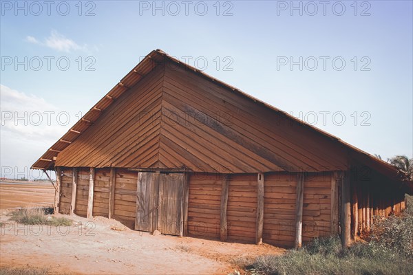 A rustic barn with a large door under a blue sky. Kampot