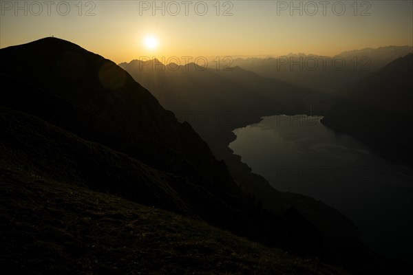 Mountain ridge with mountaineers and Swiss mountains and Lake Thun in the background at sunrise