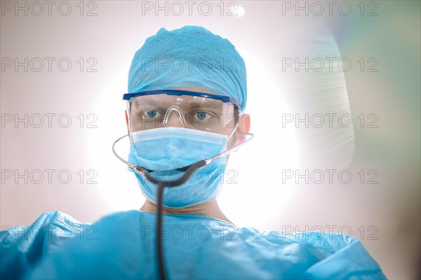 Male surgeon doctor in the operating room looking at the patient at the camera