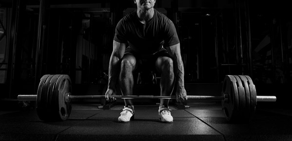 Professional athlete bent over the barbell and is preparing to lift a very heavy weight. Front view