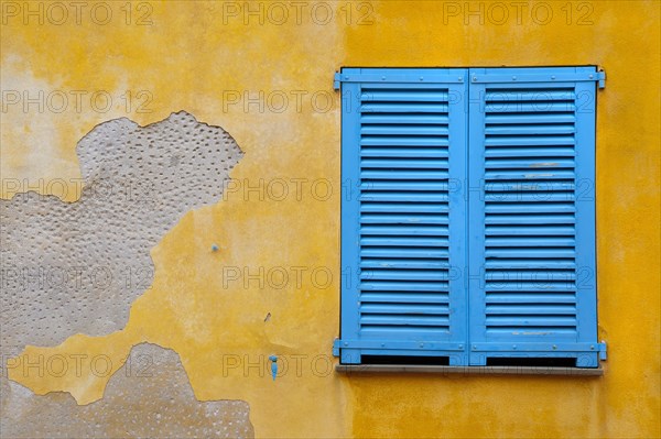 Blue shutter on yellow plaster wall