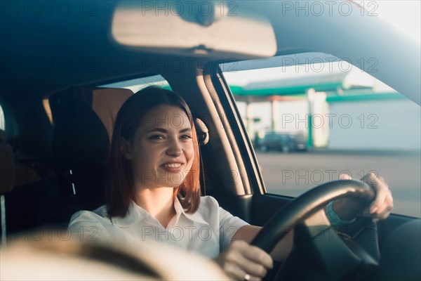 Young beautiful girl taxi driver smiling behind the wheel